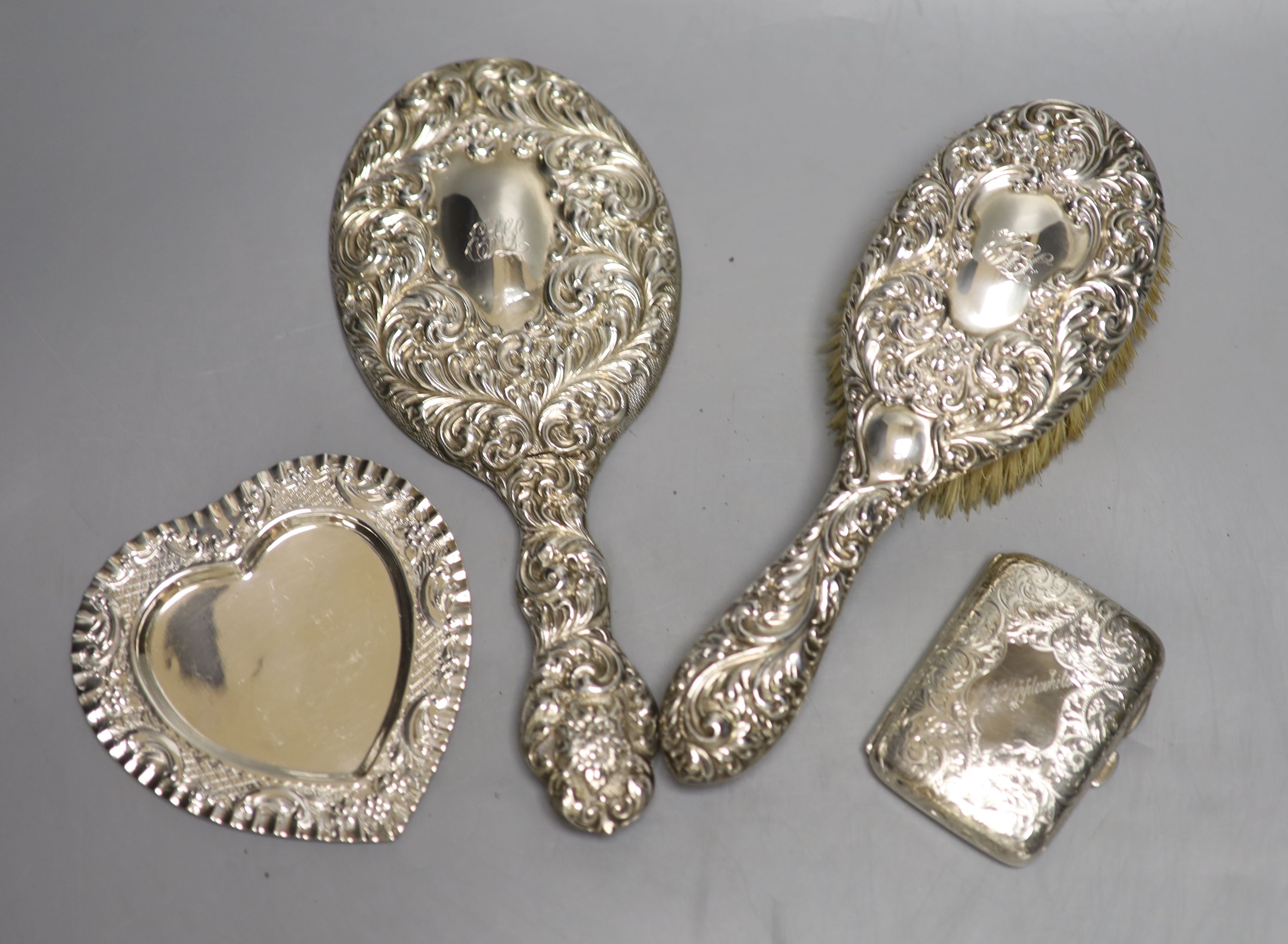 A silver cigarette case, a late Victorian silver heart shaped dish, a silver hand mirror and brush.